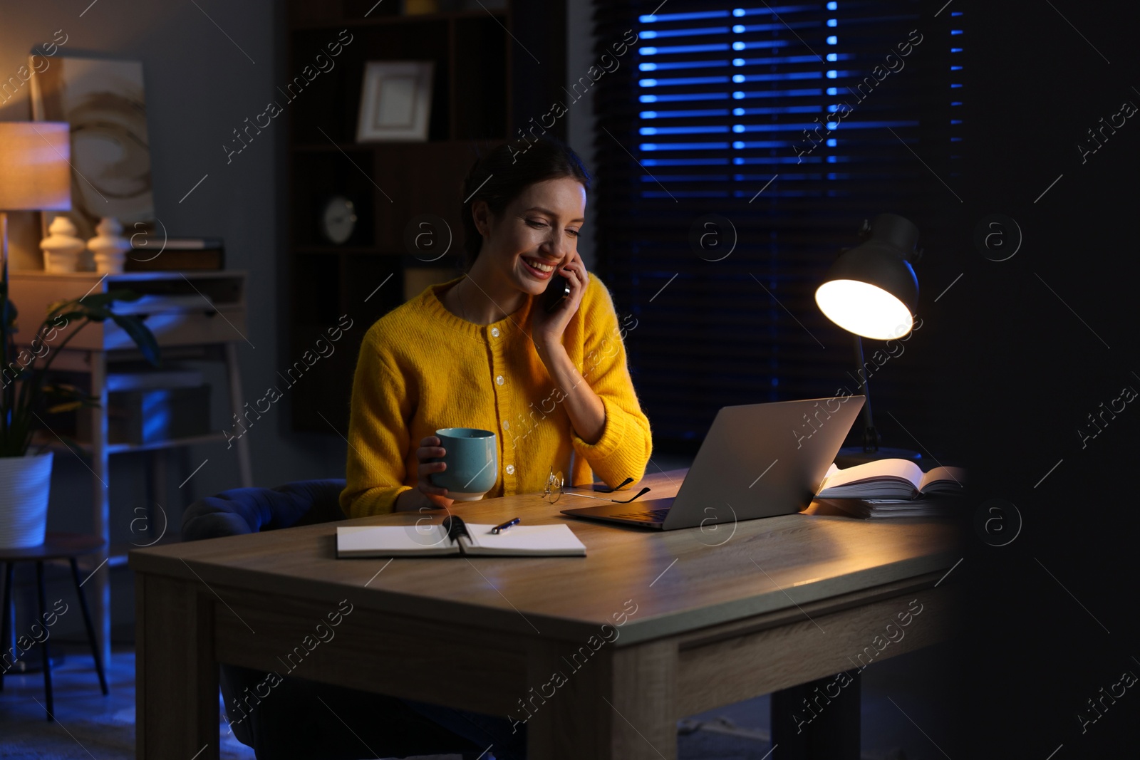 Photo of Woman talking on phone while working at desk in home office