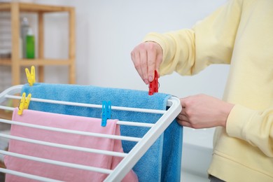 Photo of Woman hanging fresh clean laundry on drying rack at home, closeup