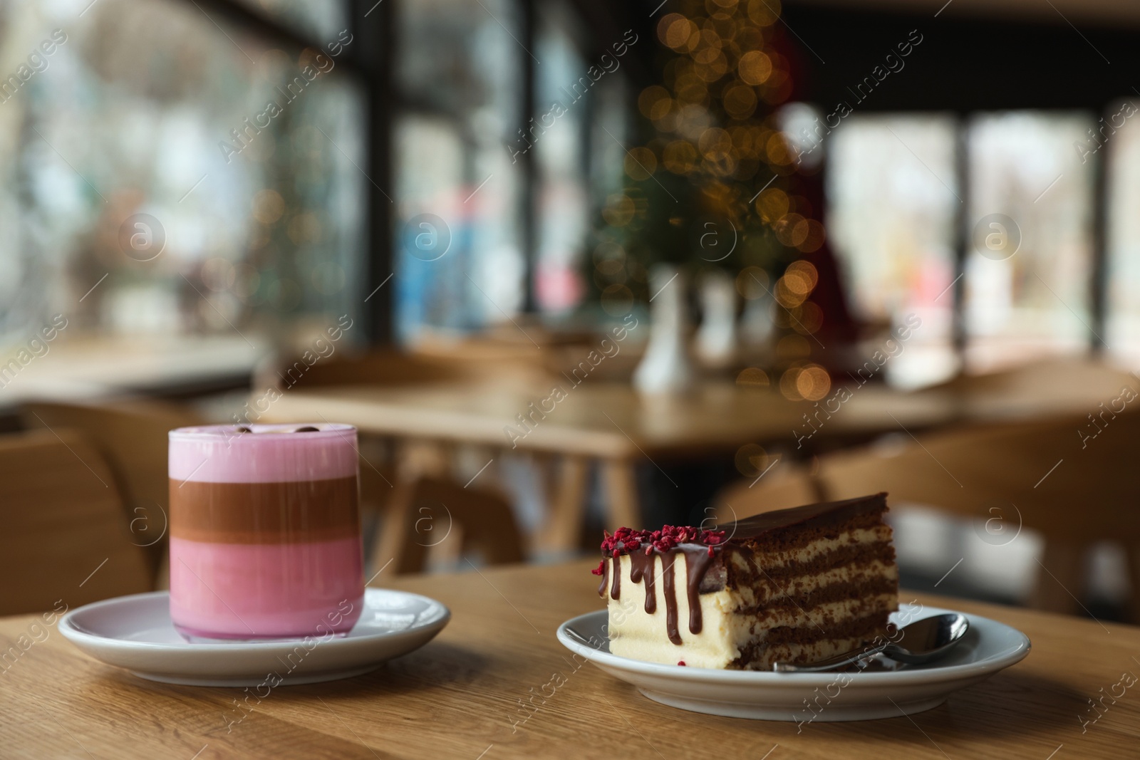 Photo of Delicious cake and pink latte served on wooden table in cafe