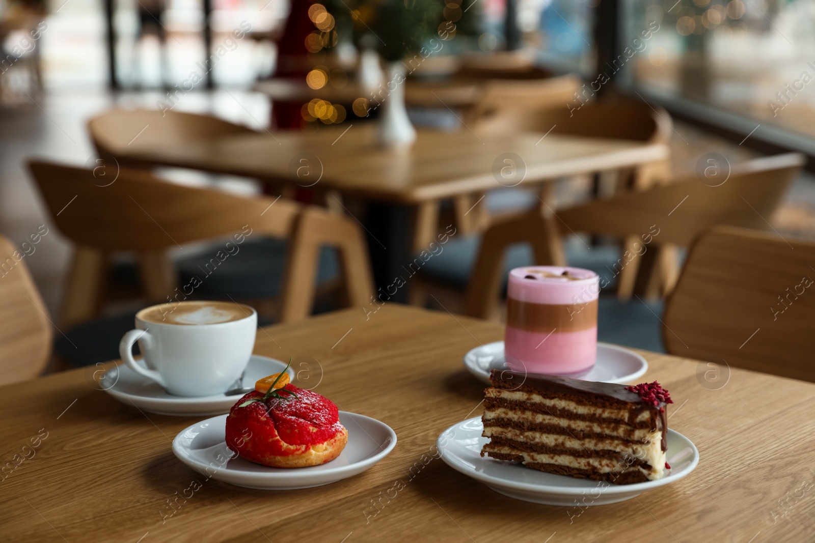 Photo of Aromatic coffee and delicious desserts served on wooden table in cafe