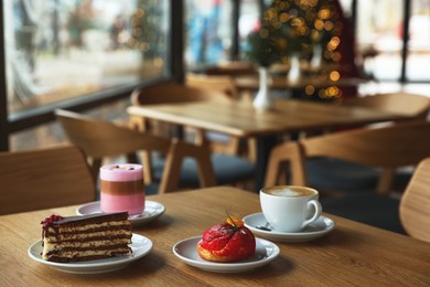 Photo of Aromatic coffee and delicious desserts served on wooden table in cafe