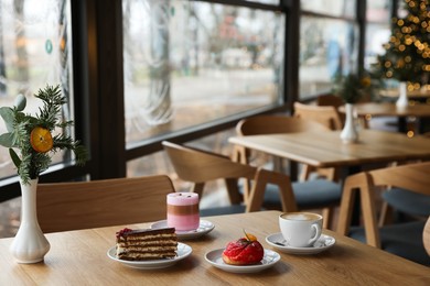 Photo of Aromatic coffee and delicious desserts served on wooden table in cafe