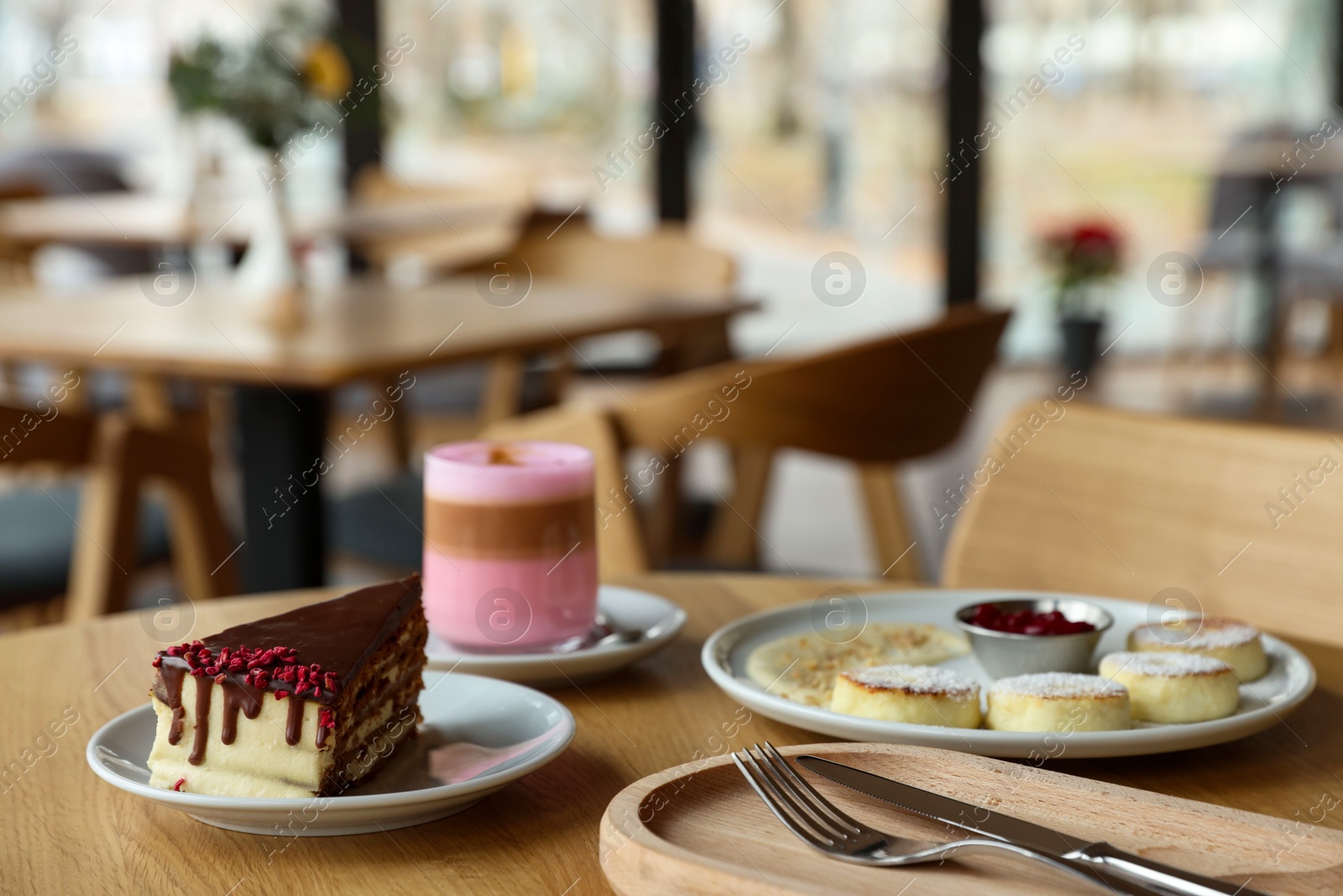 Photo of Delicious cottage cheese pancakes, cake and coffee served on wooden table in cafe