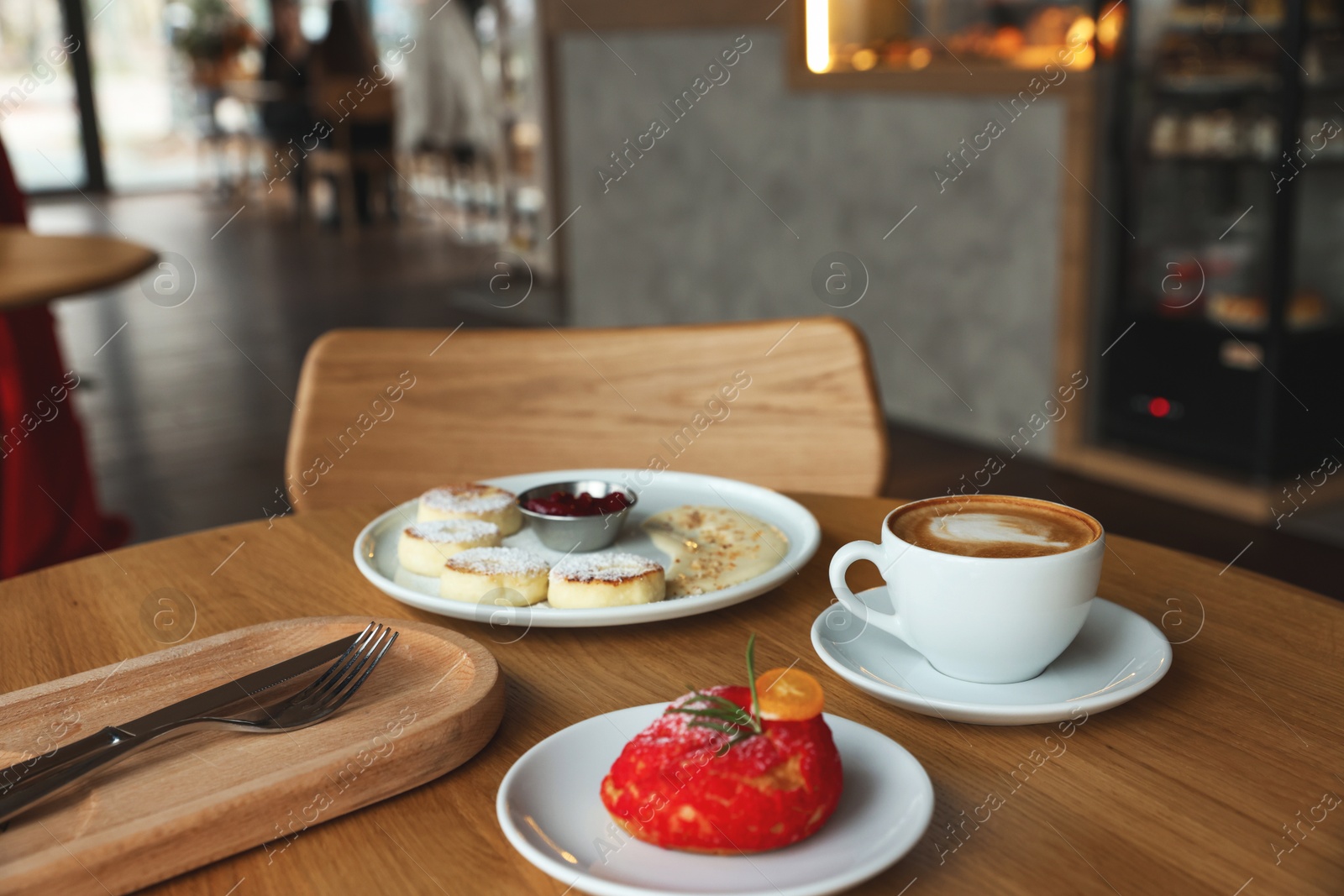 Photo of Delicious cottage cheese pancakes, dessert and coffee served on wooden table in cafe