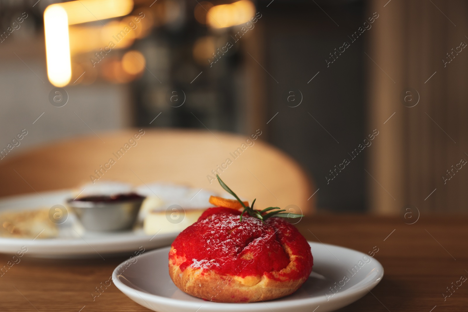 Photo of Delicious choux dessert served on wooden table in cafe, closeup