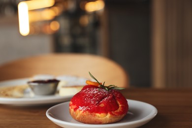 Photo of Delicious choux dessert served on wooden table in cafe, closeup