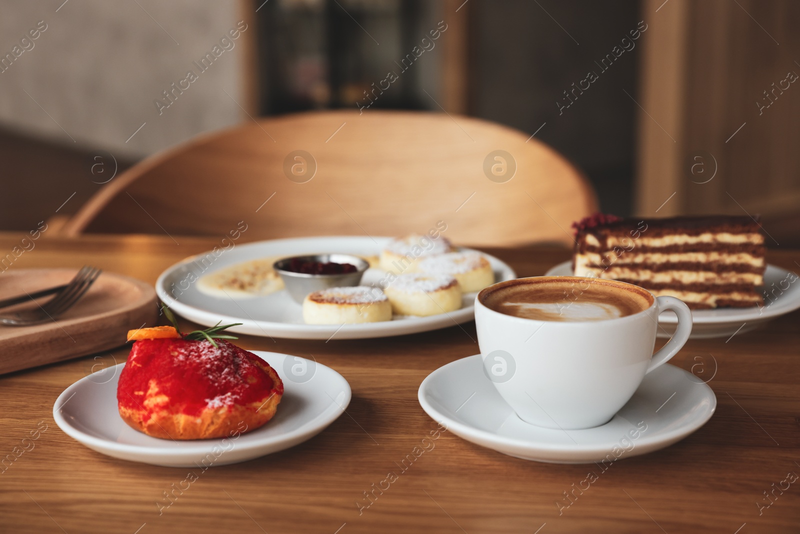 Photo of Aromatic coffee and delicious desserts served on wooden table in cafe