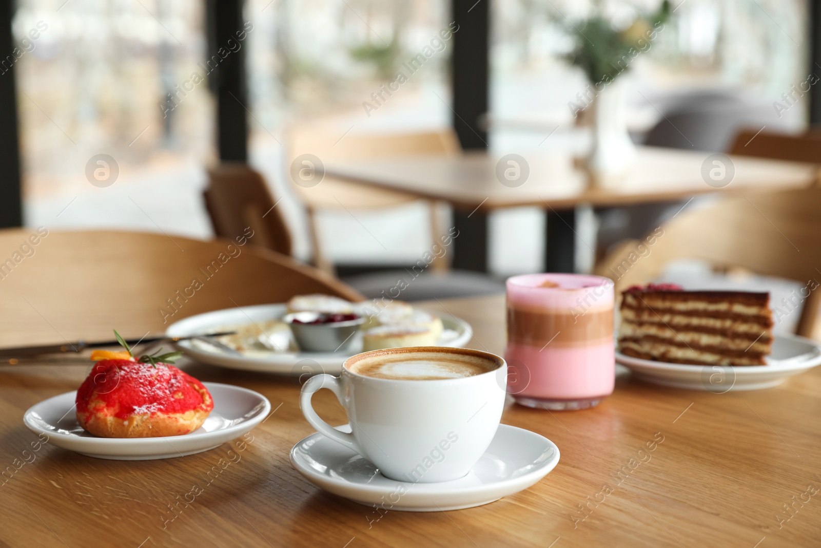 Photo of Aromatic coffee and delicious desserts served on wooden table in cafe