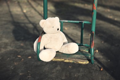 Photo of Lost white teddy bear on swing outdoors