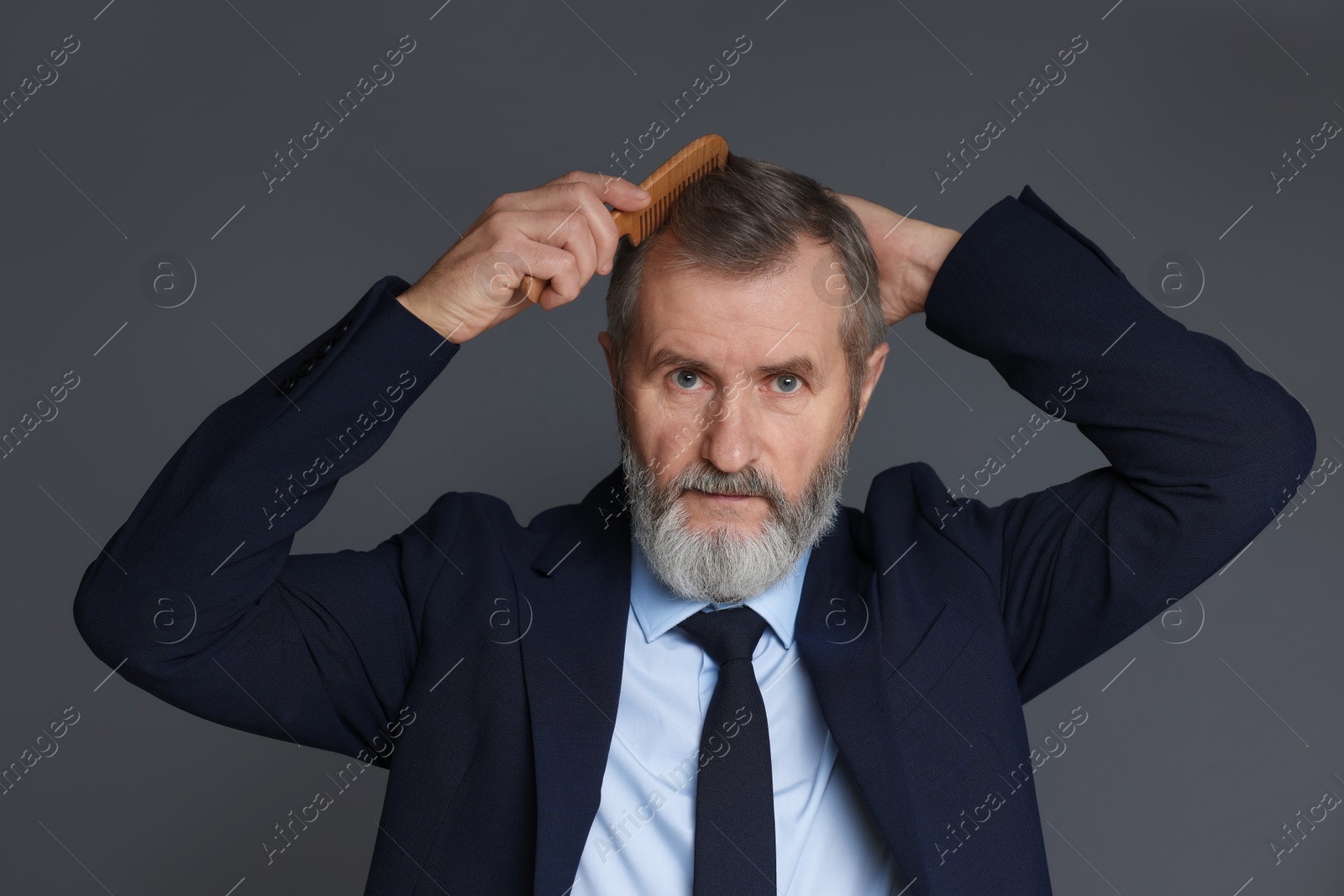 Photo of Handsome man combing his hair on dark grey background