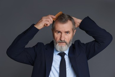 Photo of Handsome man combing his hair on dark grey background