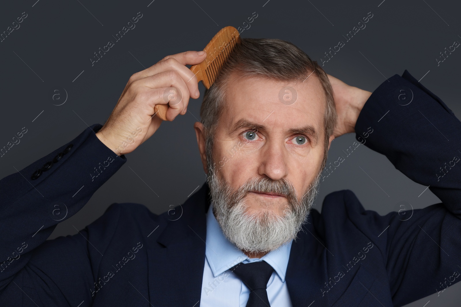 Photo of Handsome man combing his hair on dark grey background