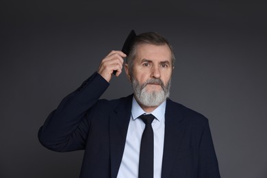 Photo of Handsome man combing his hair on dark grey background