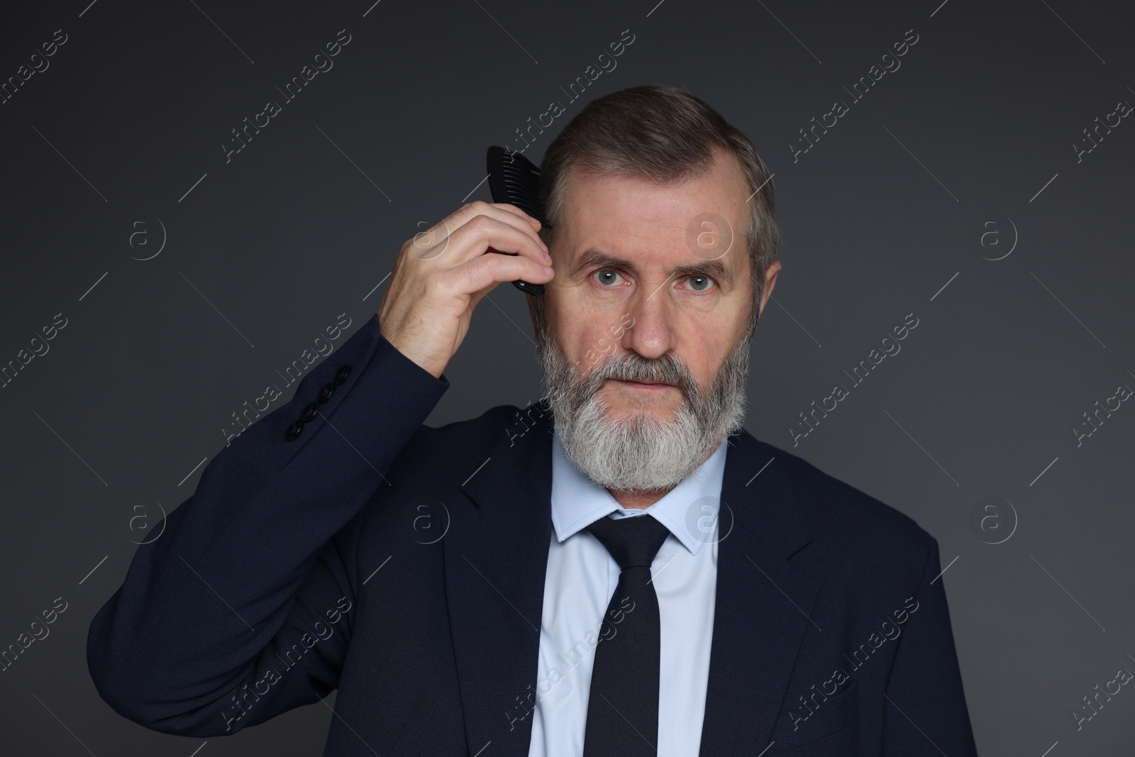 Photo of Handsome man combing his hair on dark grey background