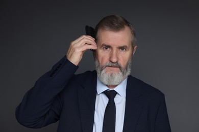 Photo of Handsome man combing his hair on dark grey background