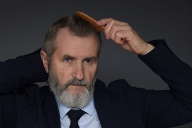 Photo of Handsome man combing his hair on dark grey background