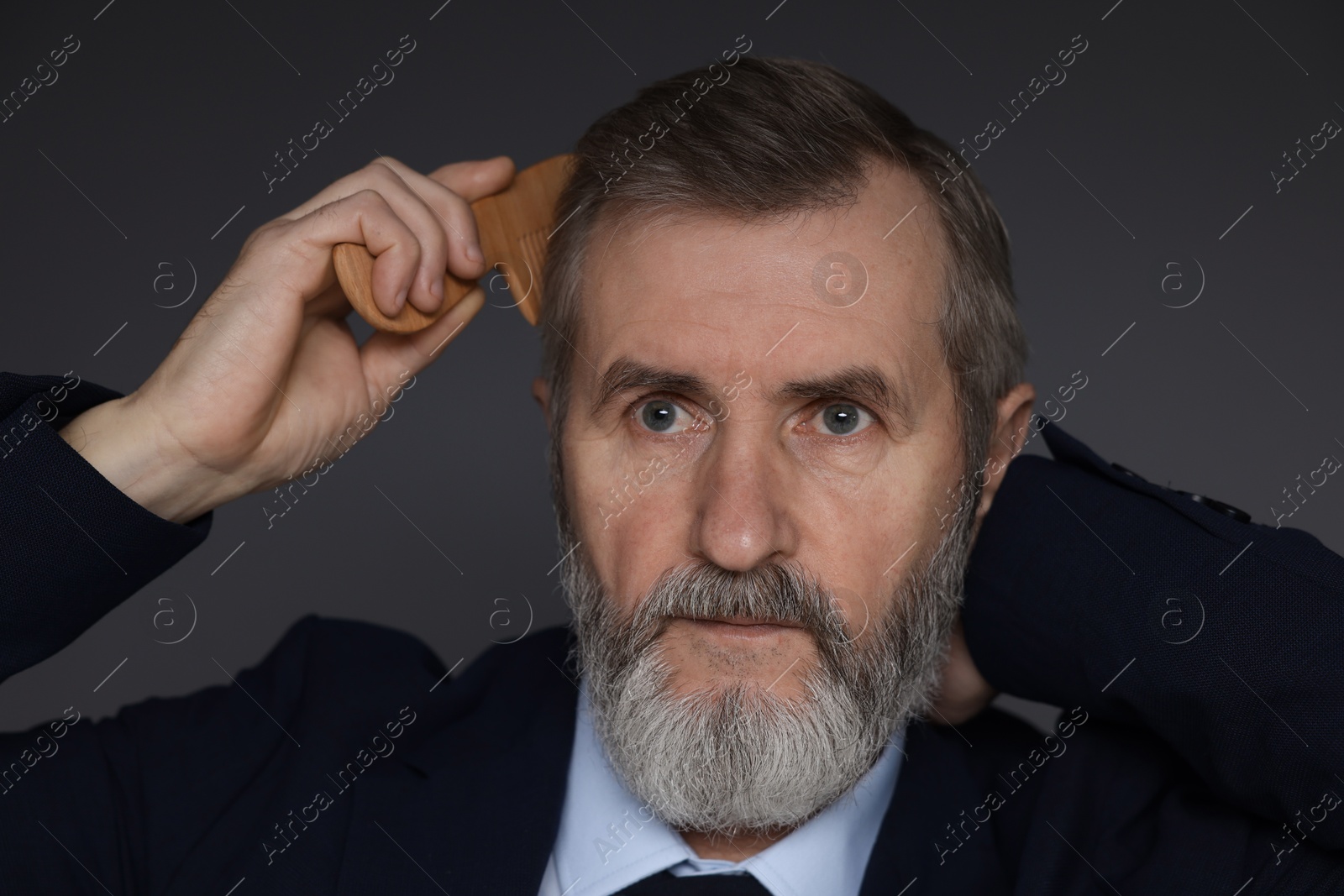 Photo of Handsome man combing his hair on dark grey background