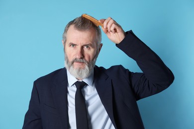 Photo of Handsome man combing his hair on light blue background