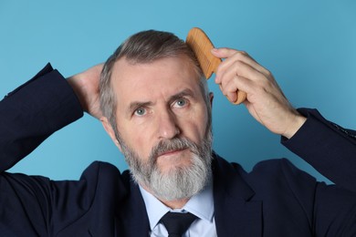 Photo of Handsome man combing his hair on light blue background