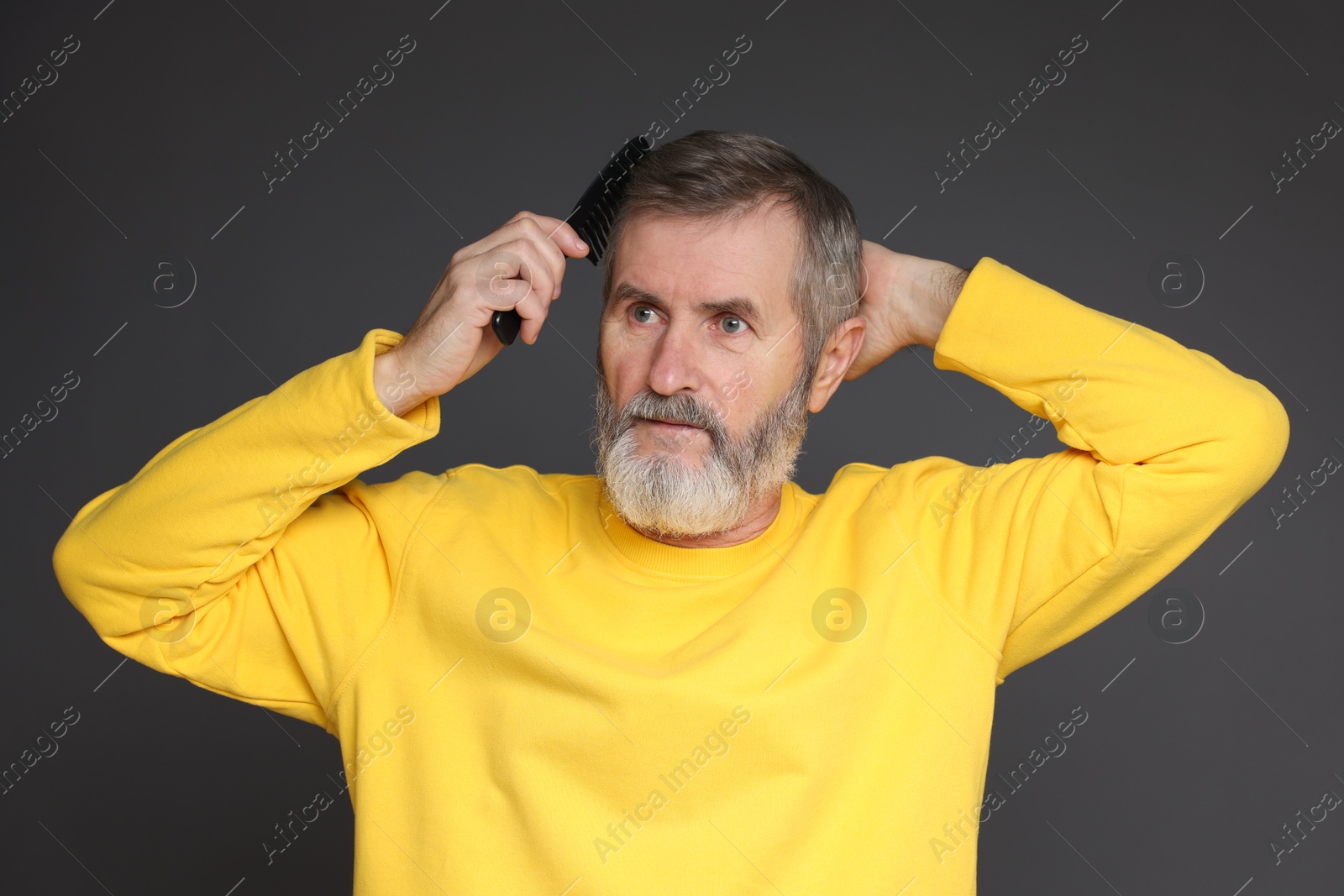 Photo of Handsome man combing his hair on dark grey background