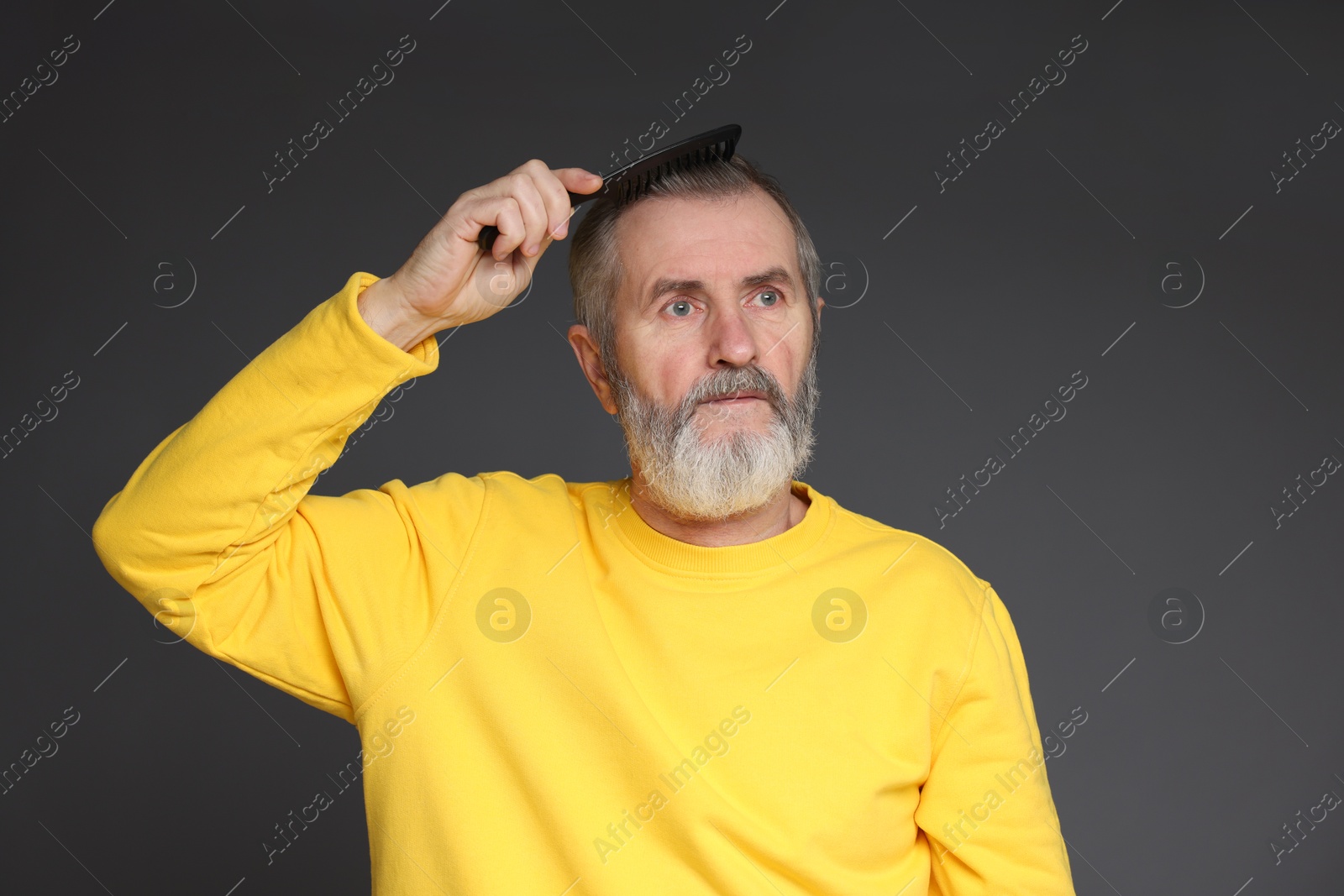 Photo of Handsome man combing his hair on dark grey background