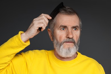 Photo of Handsome man combing his hair on dark grey background