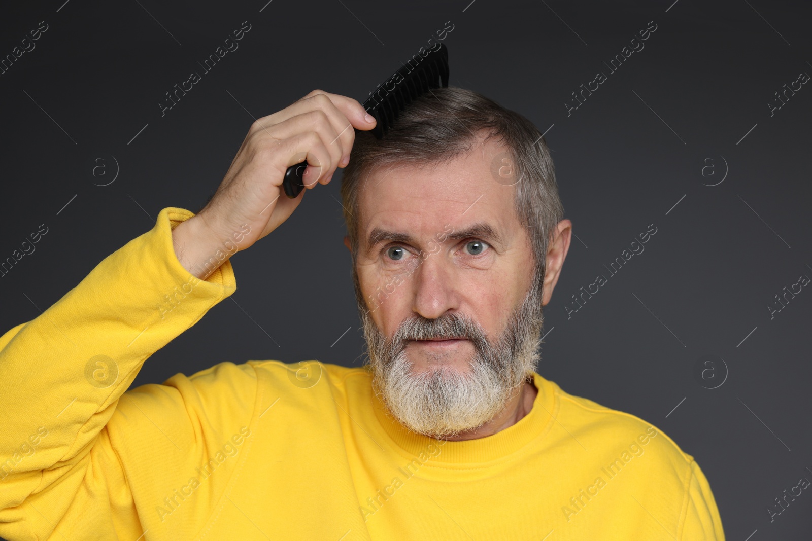 Photo of Handsome man combing his hair on dark grey background