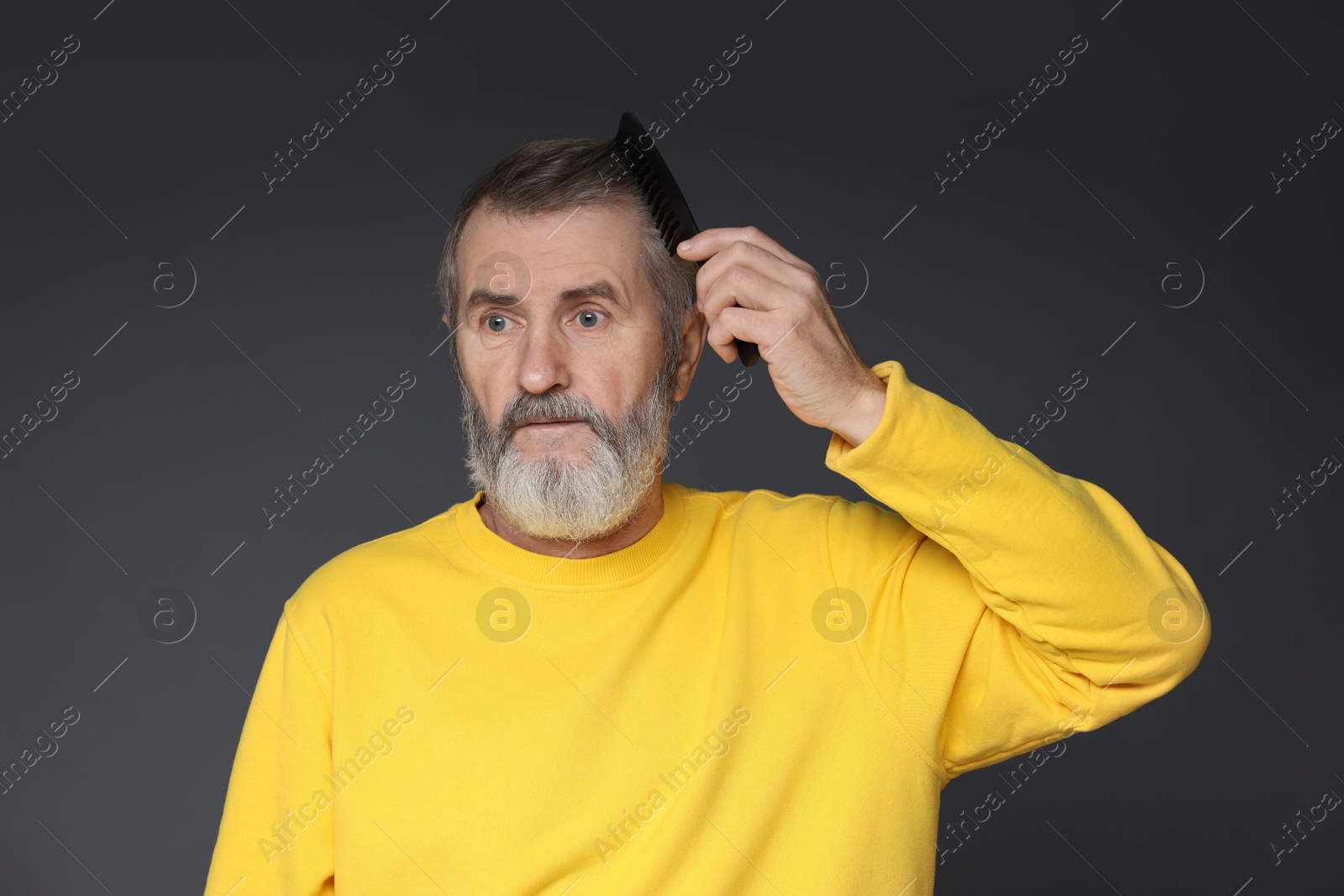 Photo of Handsome man combing his hair on dark grey background