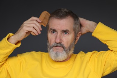 Photo of Handsome man combing his hair on dark grey background