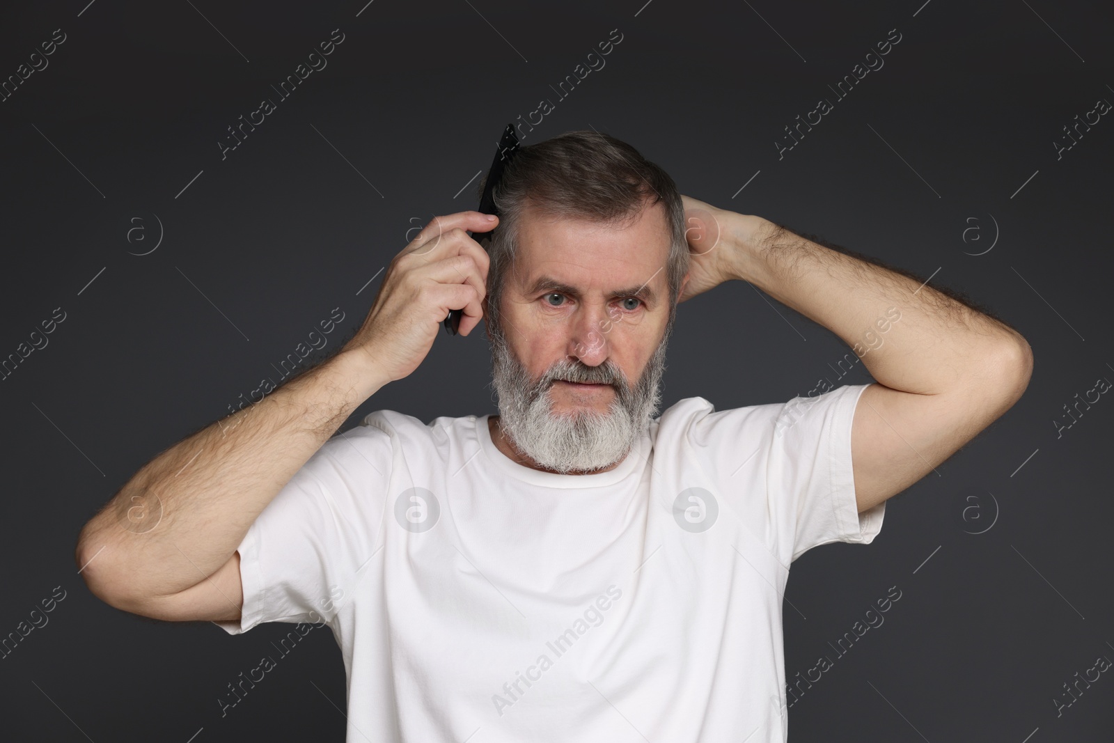 Photo of Handsome man combing his hair on dark grey background