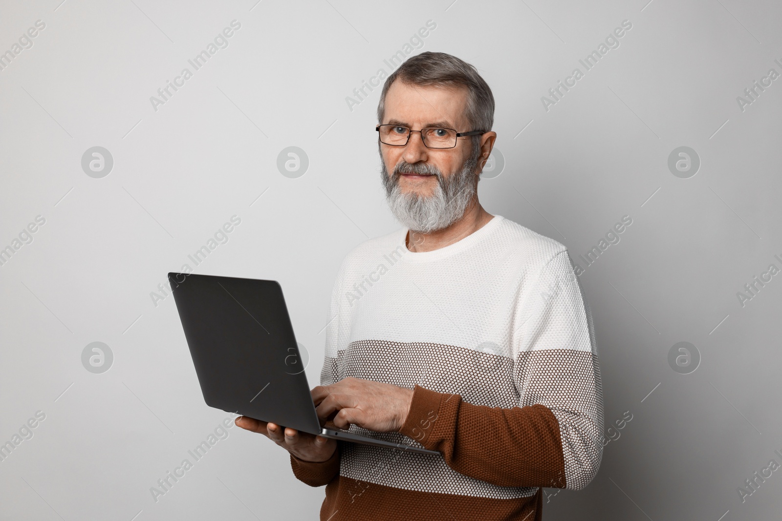 Photo of Mature man with laptop on light grey background