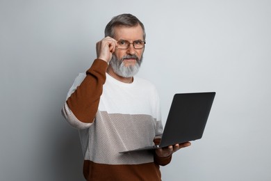 Photo of Mature man with laptop on light grey background