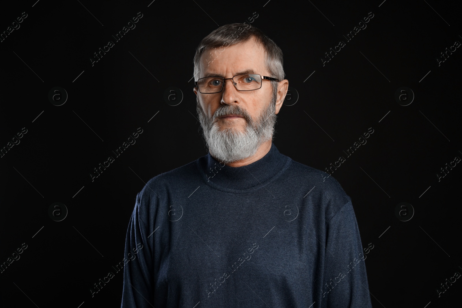 Photo of Portrait of mature man in glasses on black background