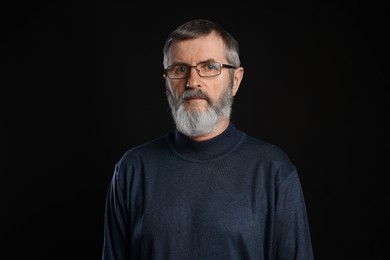 Photo of Portrait of mature man in glasses on black background