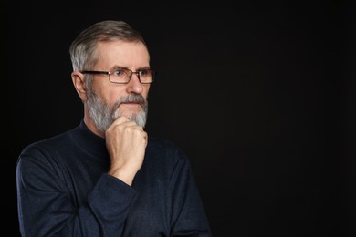 Photo of Portrait of mature man in glasses on black background, space for text