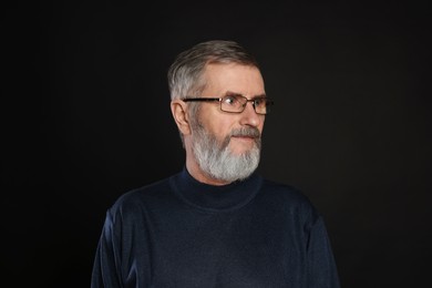 Photo of Portrait of mature man in glasses on black background