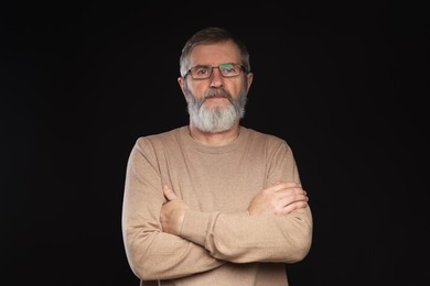 Photo of Portrait of mature man with crossed arms on black background