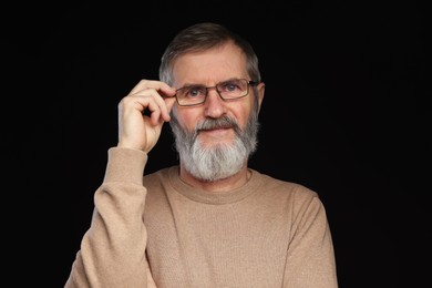 Photo of Portrait of mature man in glasses on black background