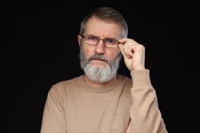 Photo of Portrait of mature man in glasses on black background