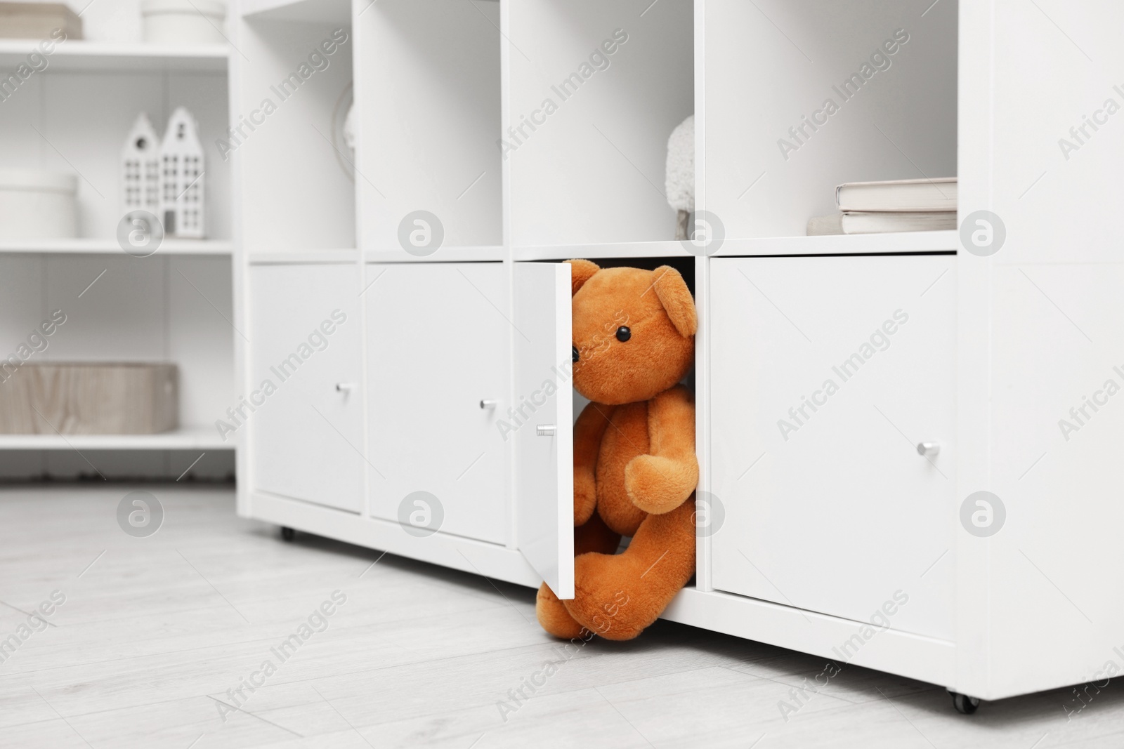 Photo of Brown teddy bear in shelving unit in room