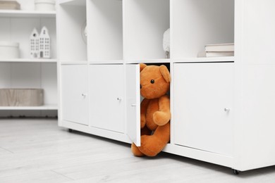 Photo of Brown teddy bear in shelving unit in room