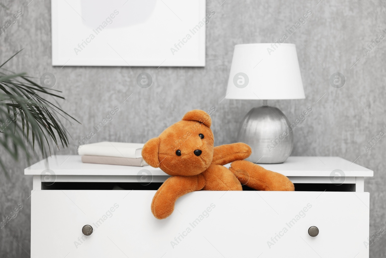 Photo of Teddy bear in open drawer of dresser in room