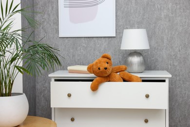 Photo of Teddy bear in open drawer of dresser in room