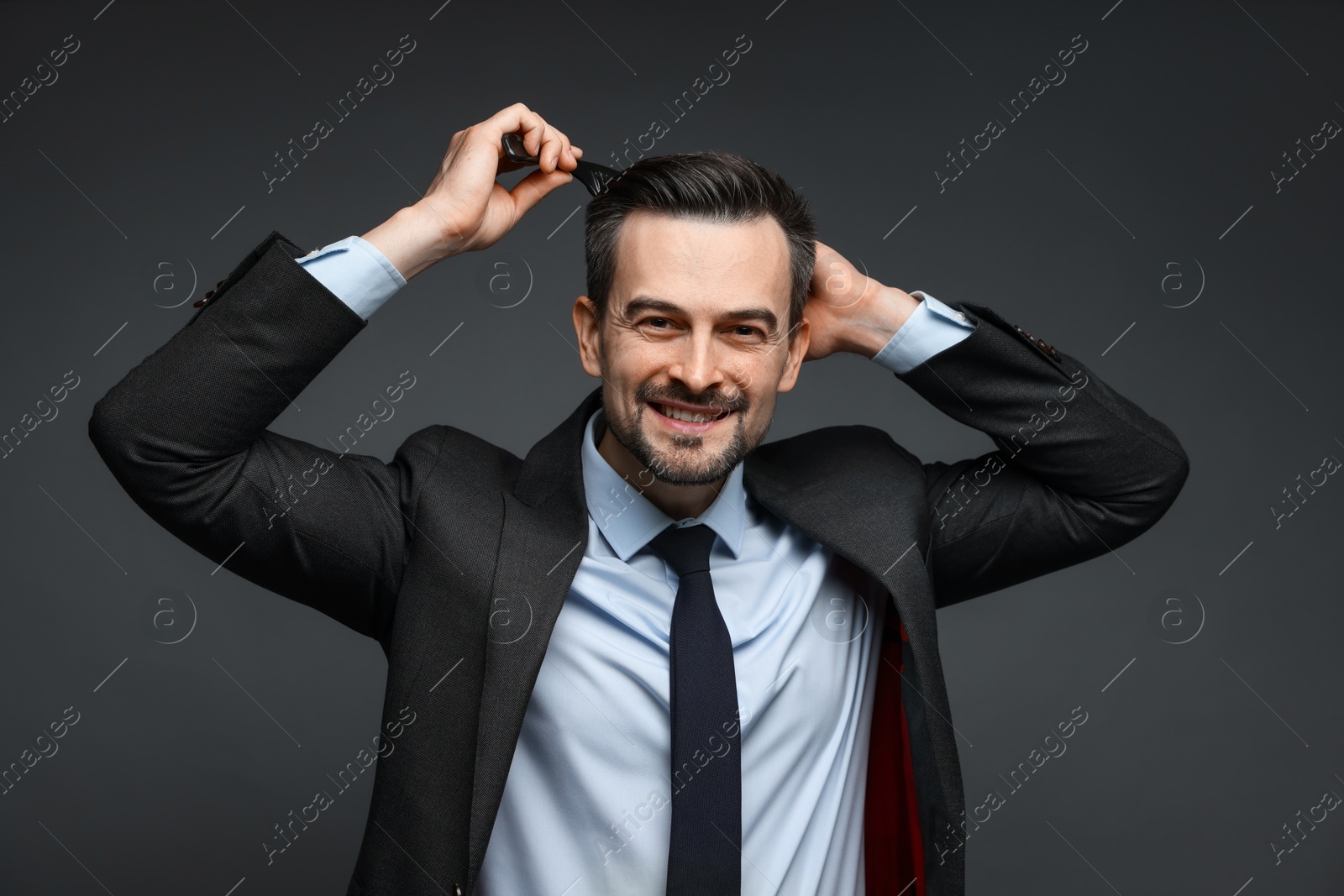 Photo of Handsome businessman combing his hair on dark background