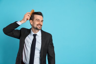 Photo of Handsome man stylish his hair with comb on light blue background