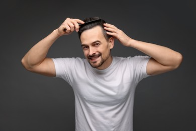 Photo of Handsome man combing his hair on dark background