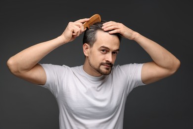 Photo of Handsome man combing his hair on dark background