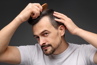 Photo of Handsome man combing his hair on dark background