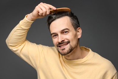 Photo of Handsome man combing his hair on dark background