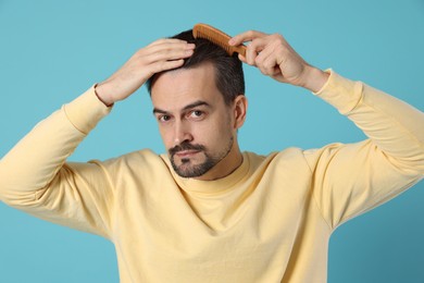 Photo of Handsome man stylish his hair with comb on light blue background